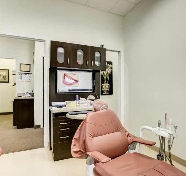 Modern dental treatment room with reclining chair and monitor.